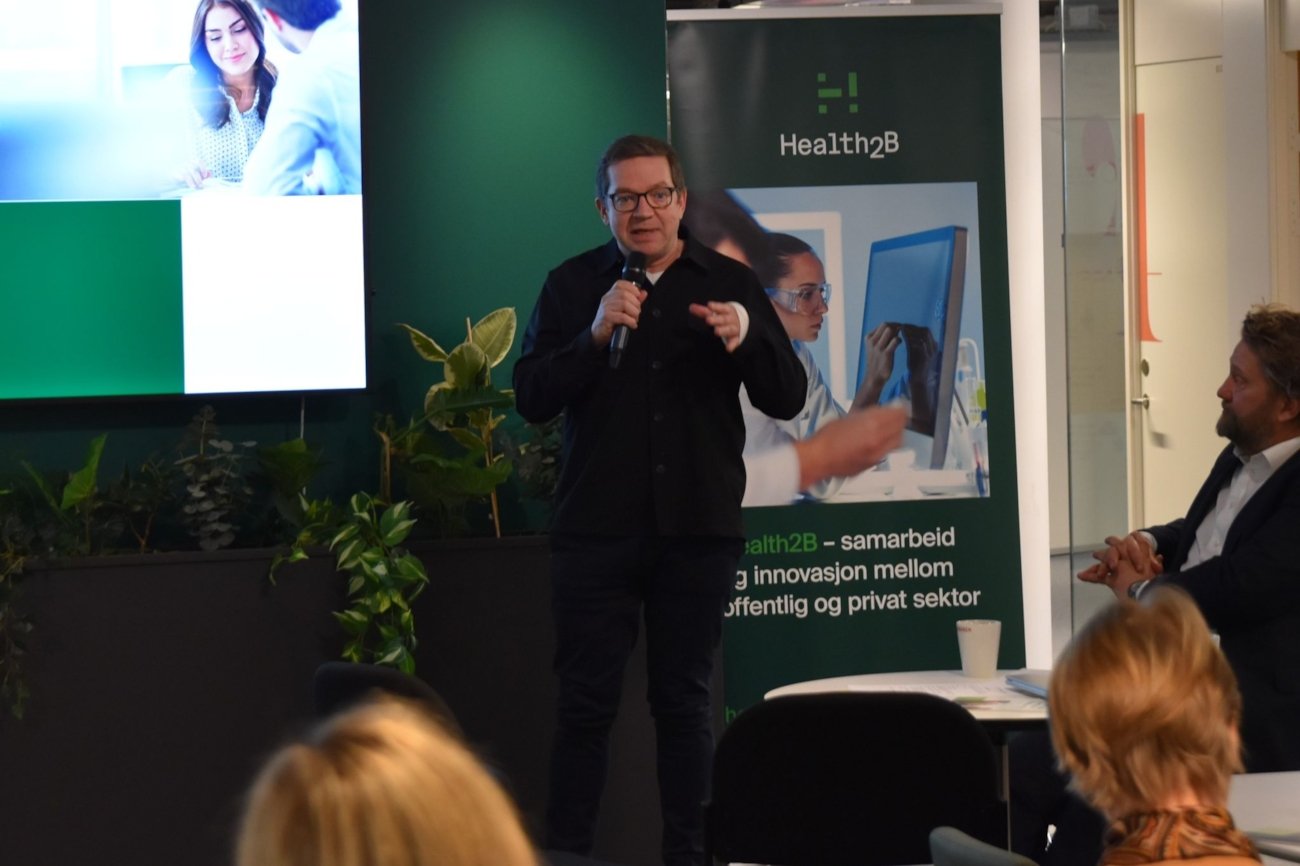 En mann står og snakker i en mikrofon.