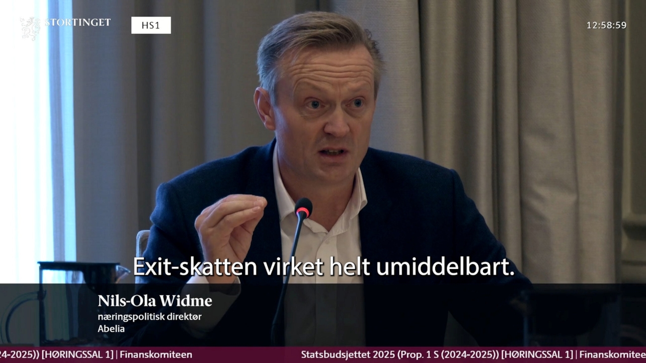 En sittende mann snakker i en mikrofon.