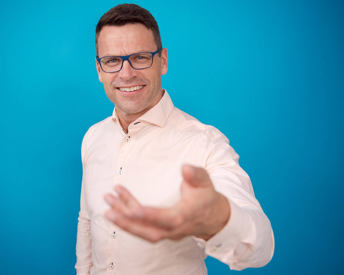 En person smiler til kamera med en utstrekt hånd.