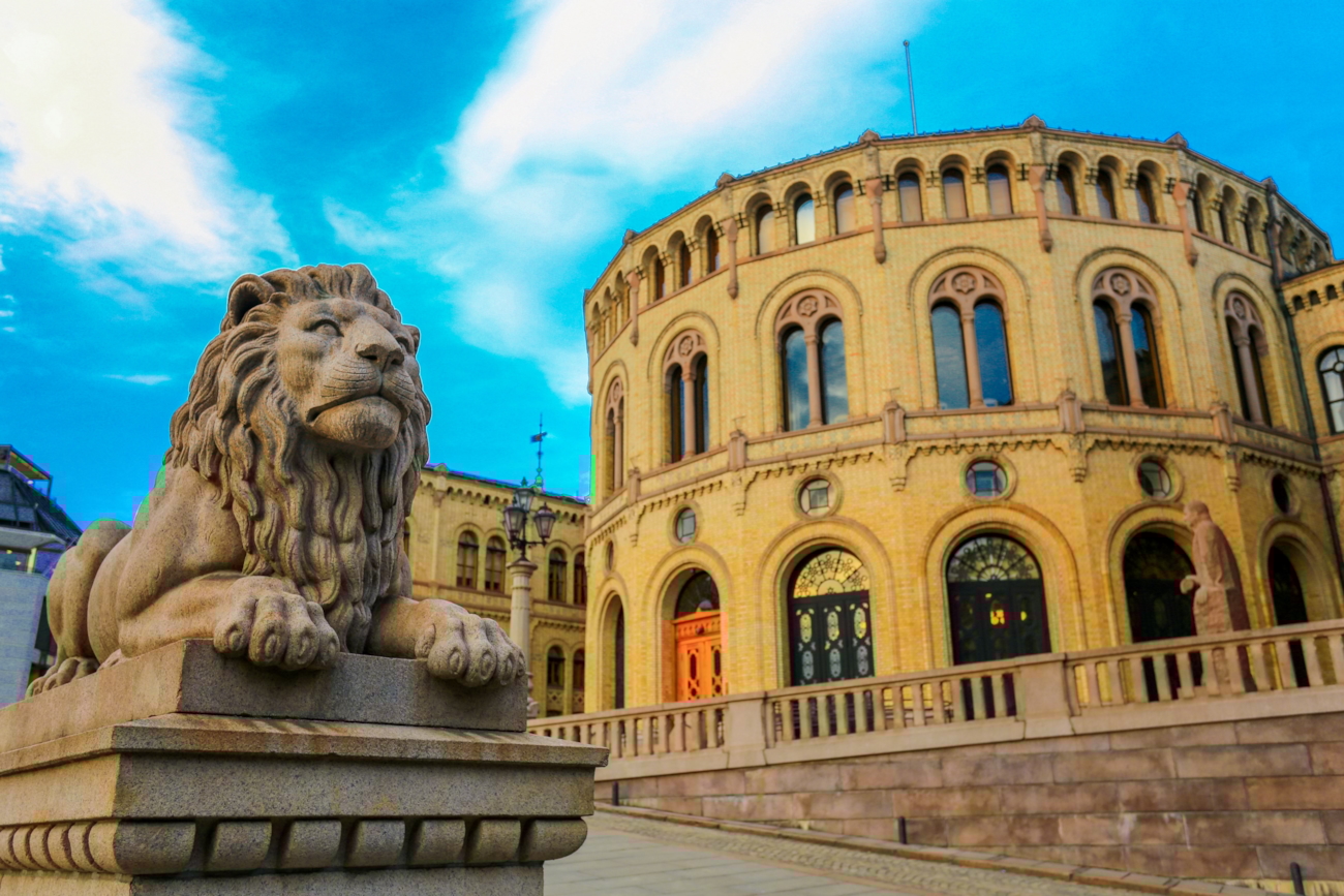 Bilde av løven på stortinget med stortinget i bakgrunnen