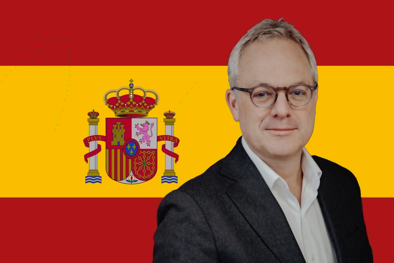 Øystein E. Søreide ser inn i kameraet med det spanske flagget bak seg.