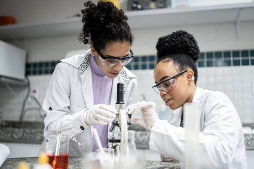 Bilde av to kvinner som utfører et eksperiment i et reagensrør.