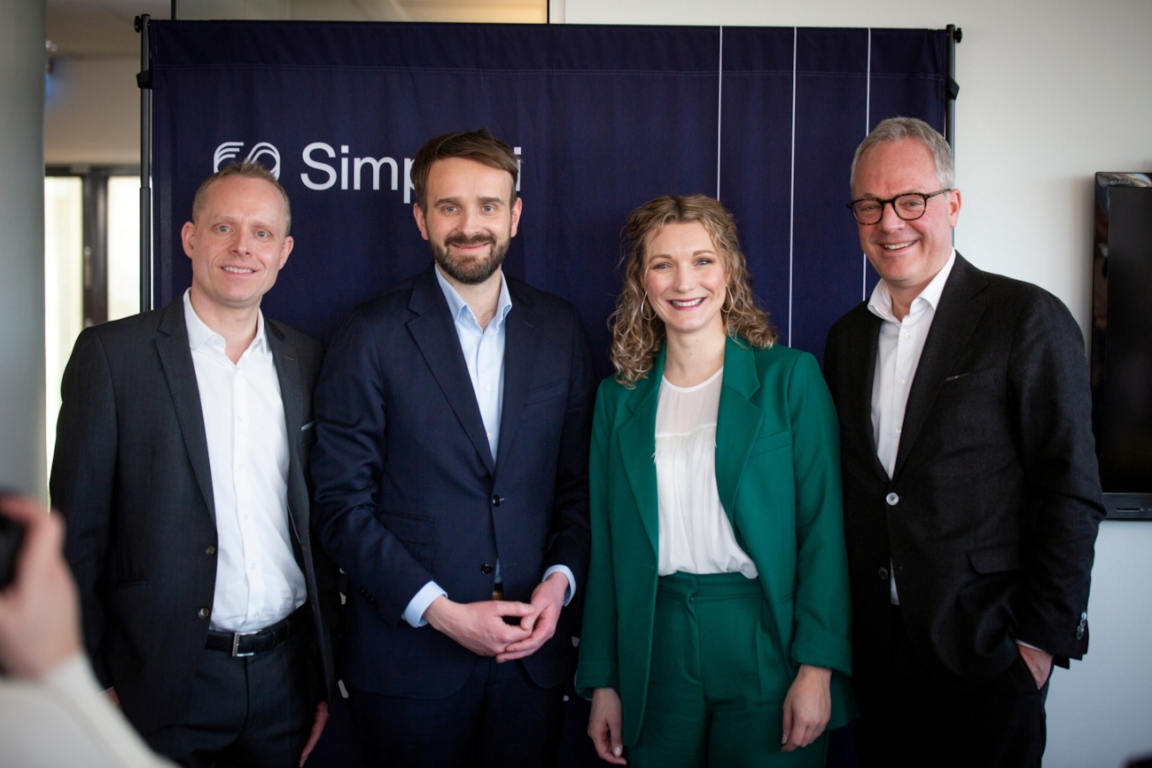 Tre menn og en dame står oppstilt og smiler.