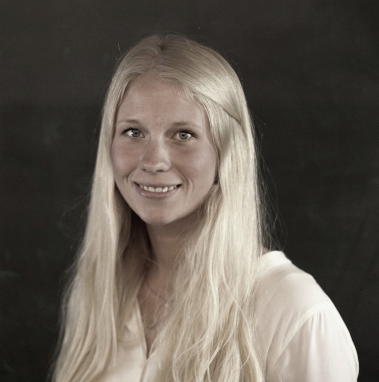 En kvinne smiler og ser i kamera.