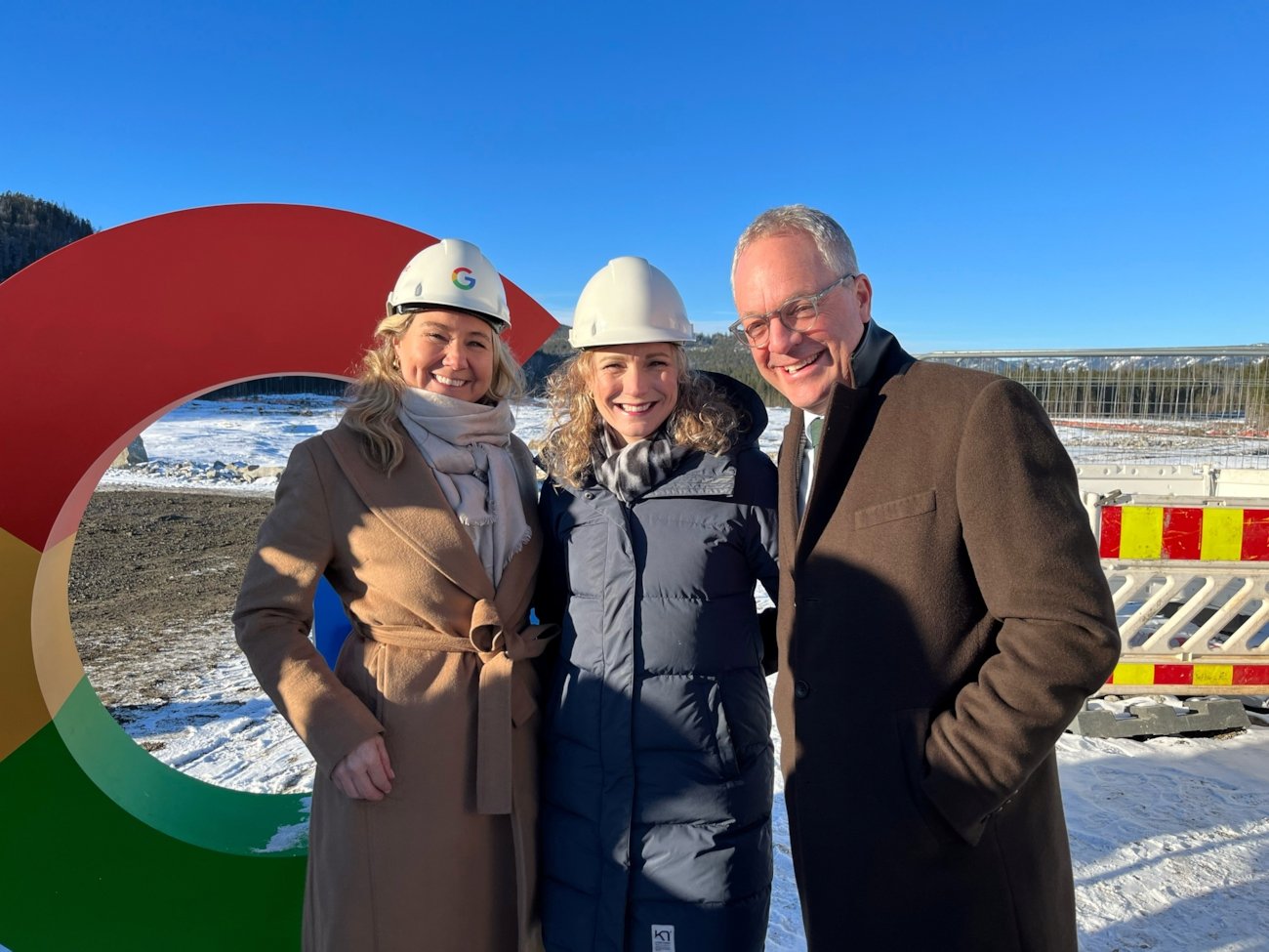 To damer med bygningshjelm og en mann står utendørs med en "Google-G" i bakgrunnen.
